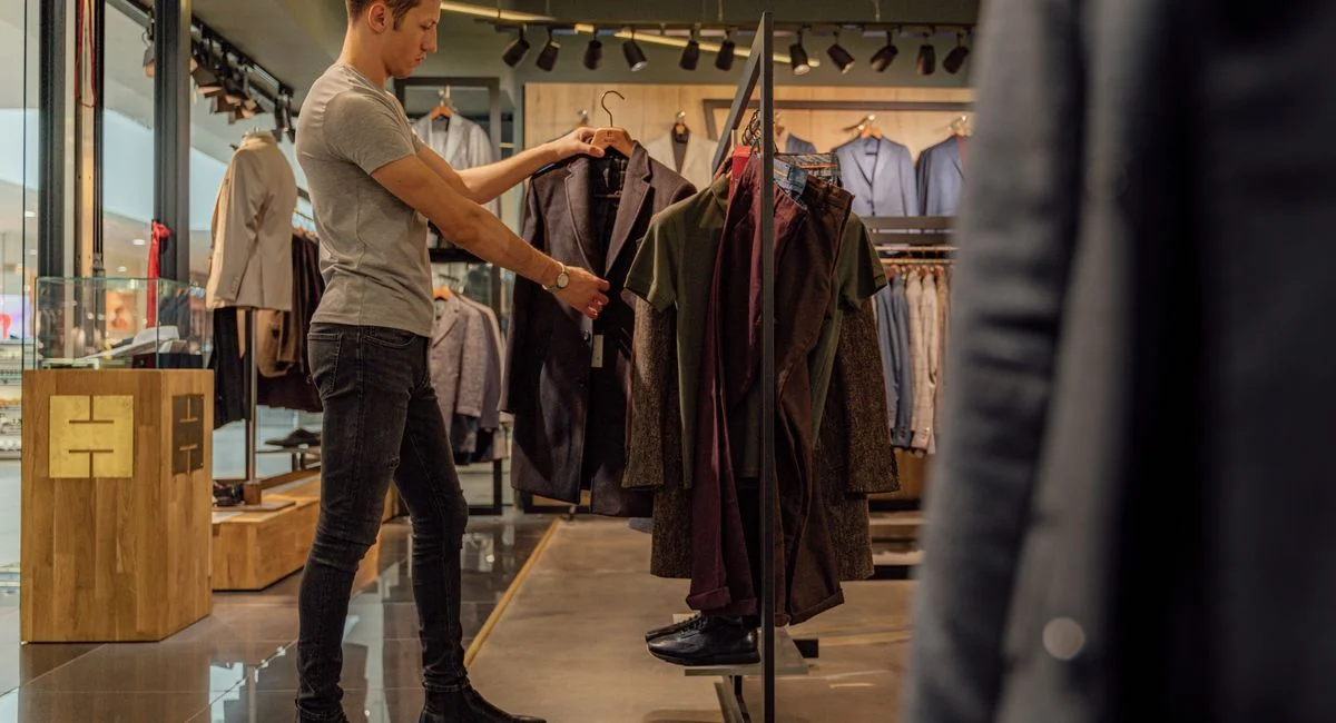 A man browsing stylish blazers in a modern clothing store, focusing on men's fashion.