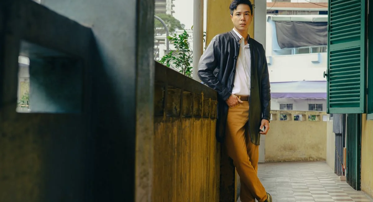 Casual man leaning on a vintage-style balcony indoors, day scene.